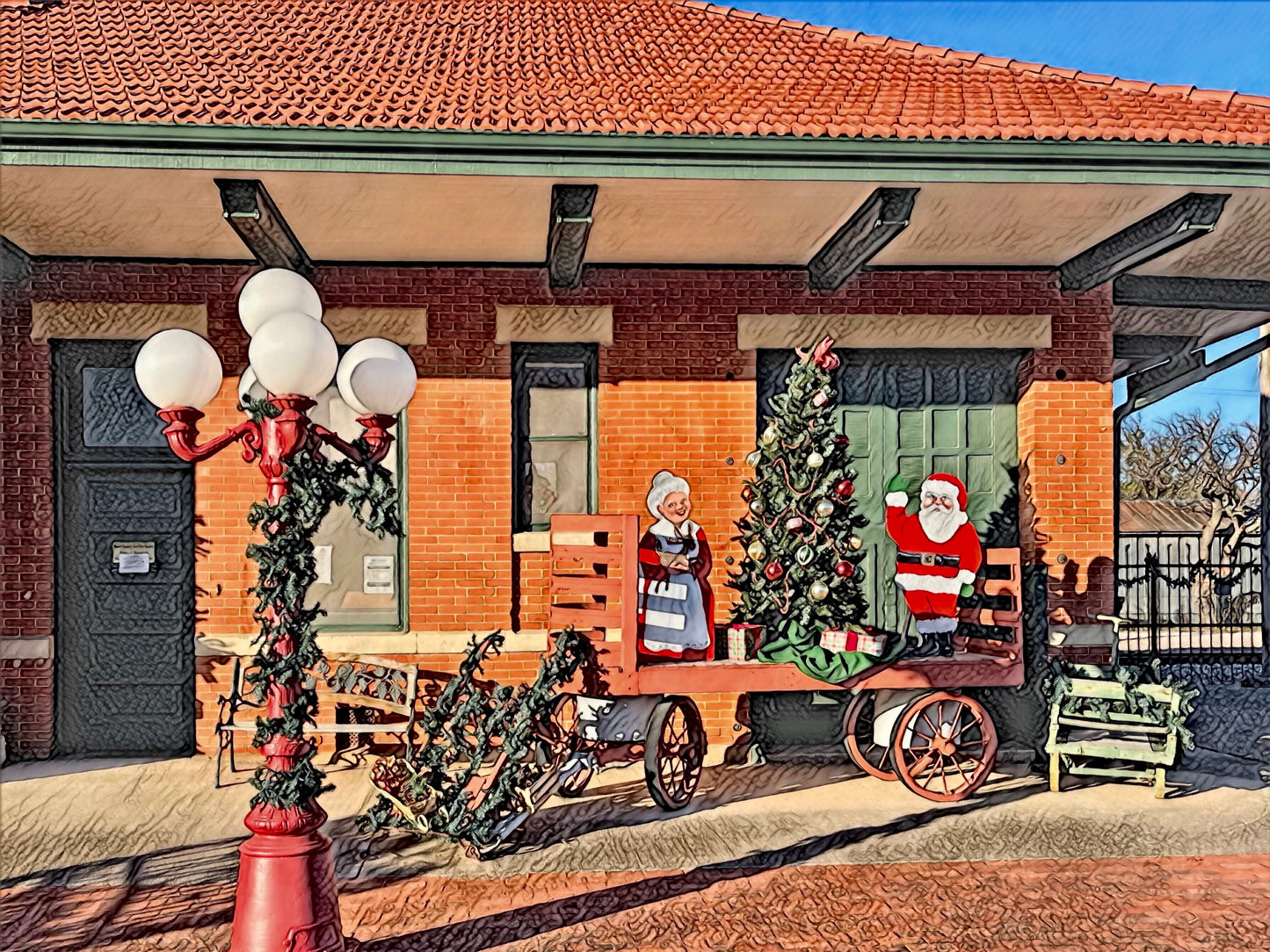 red brick with red spanish tile roof and green doorr ailroad station. Wagon with Mr. and Mrs. Claus waving. Old fasioned lampost in front with globe lights and garland wrapped on pole