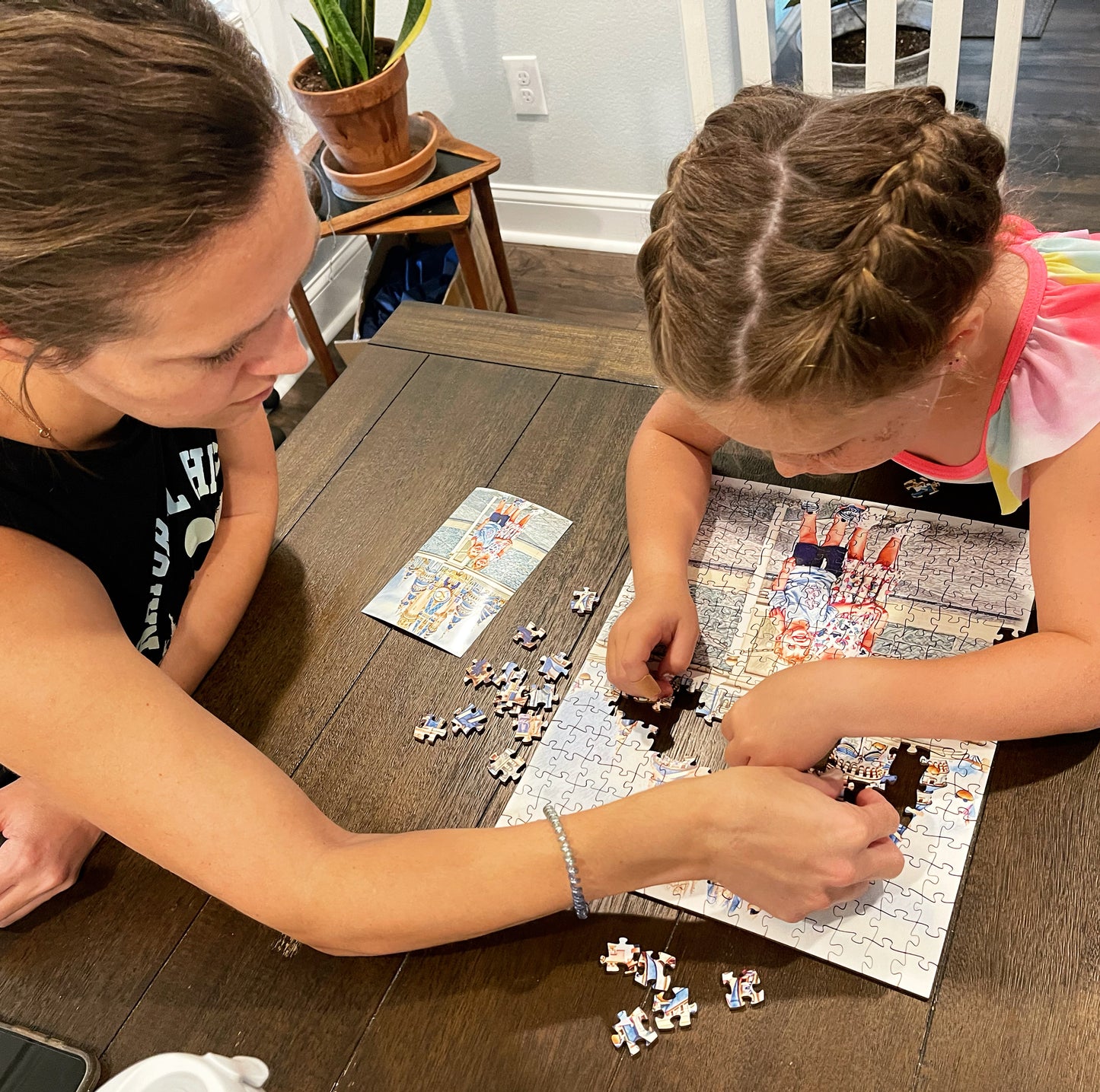 Mother helping young daughter work puzzle