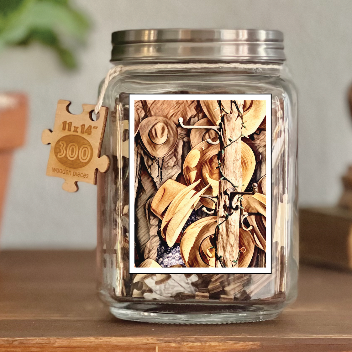 Image of puzzle shown on display clear glass Mason style jar with silver metal crew on lid. Exposes puzzle pieces inside the jar. Wooden tag hangs down the side of the jar with kite string from lid of jar with size and piece count engraved into it.