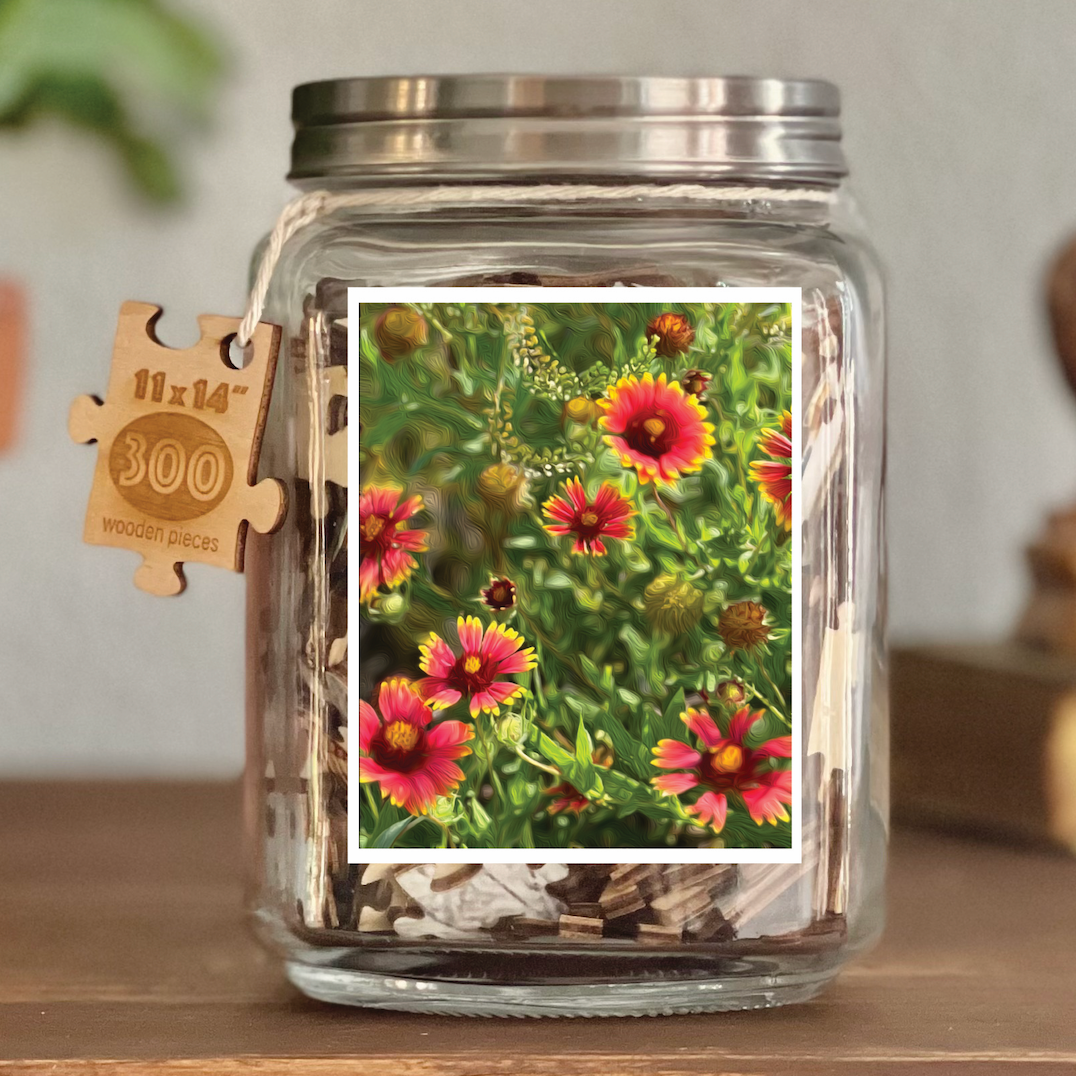 Image of puzzle shown on display clear glass Mason style jar with silver metal crew on lid. Exposes puzzle pieces inside the jar. Wooden tag hangs down the side of the jar with kite string from lid of jar with size and piece count engraved into it.